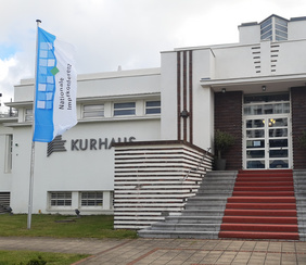 8. Nationale Impfkonferenz im Kurhaus Warnemünde Fahne der Nationalen Impfkonferenz weht vor dem Eingangsbereich des Kurhauses Warnemünde